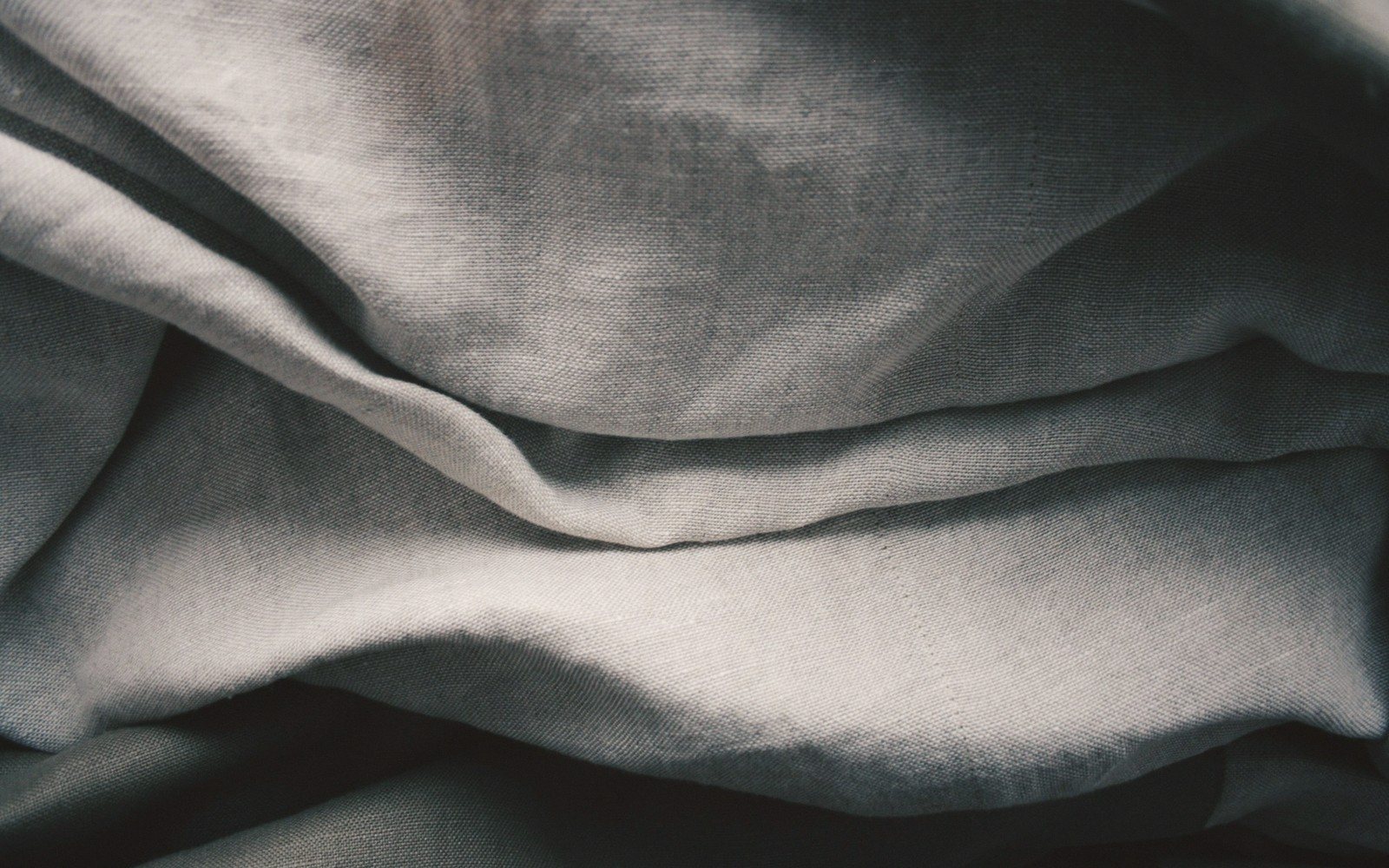 Close-up of soft folds and creases in pale grey linen fabric